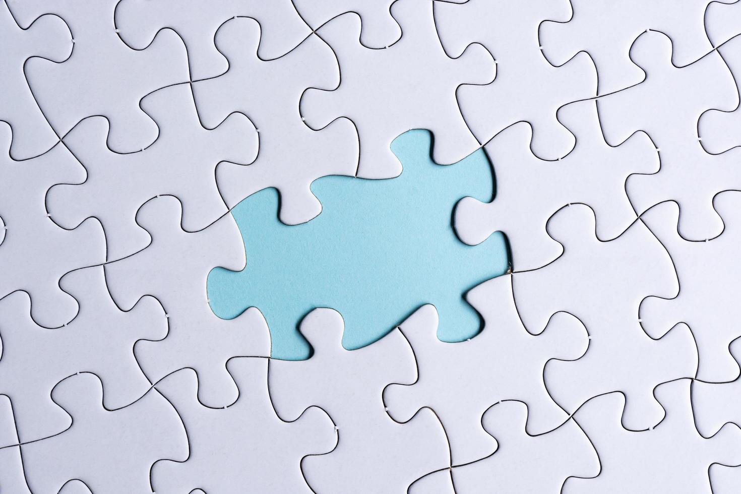 Piece of jigsaw puzzle on blue paper. Directly above. Copy space. photo