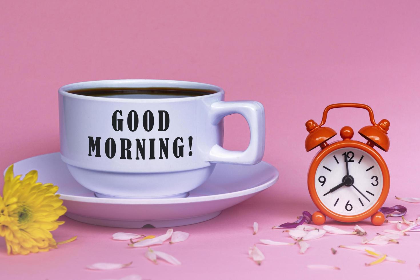 Good morning text on white coffee cup with alarm clock set at 8 o'clock