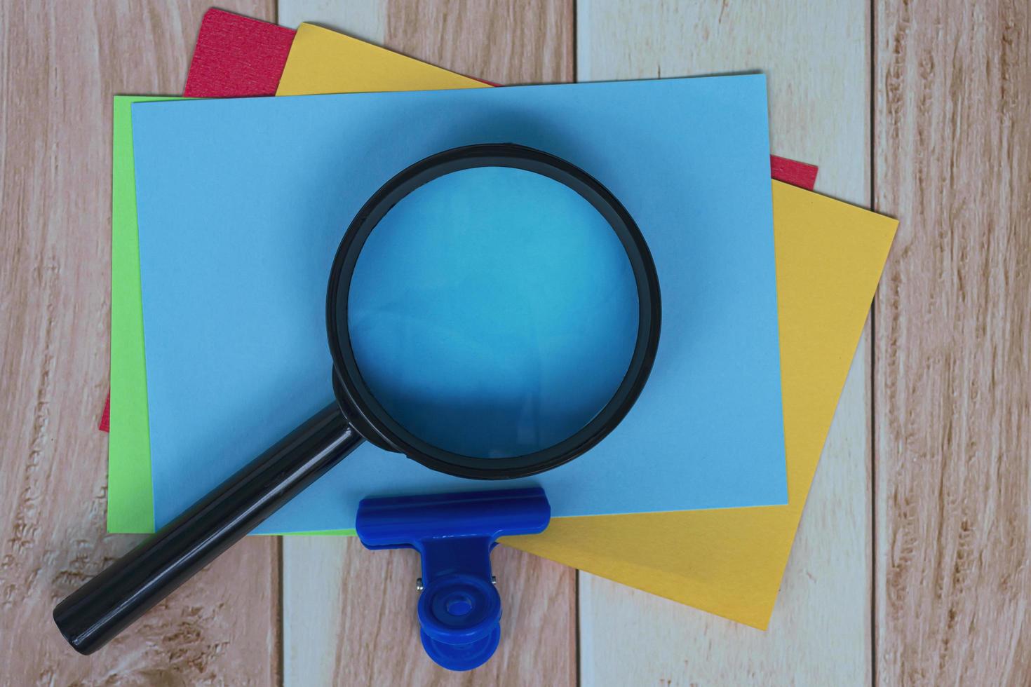 Colorful Adhesive Note With Magnifying Glass On Wooden Desk. Business Concept. photo