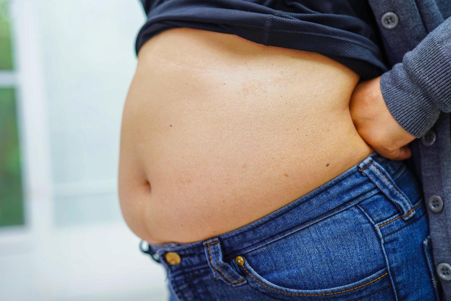 la mujer asiática muestra un vientre gordo de gran tamaño con sobrepeso y obesidad en la oficina. foto