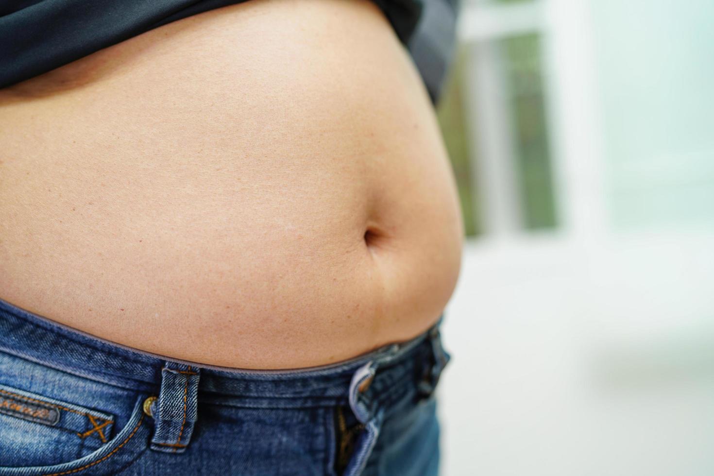 la mujer asiática muestra un vientre gordo de gran tamaño con sobrepeso y obesidad en la oficina. foto