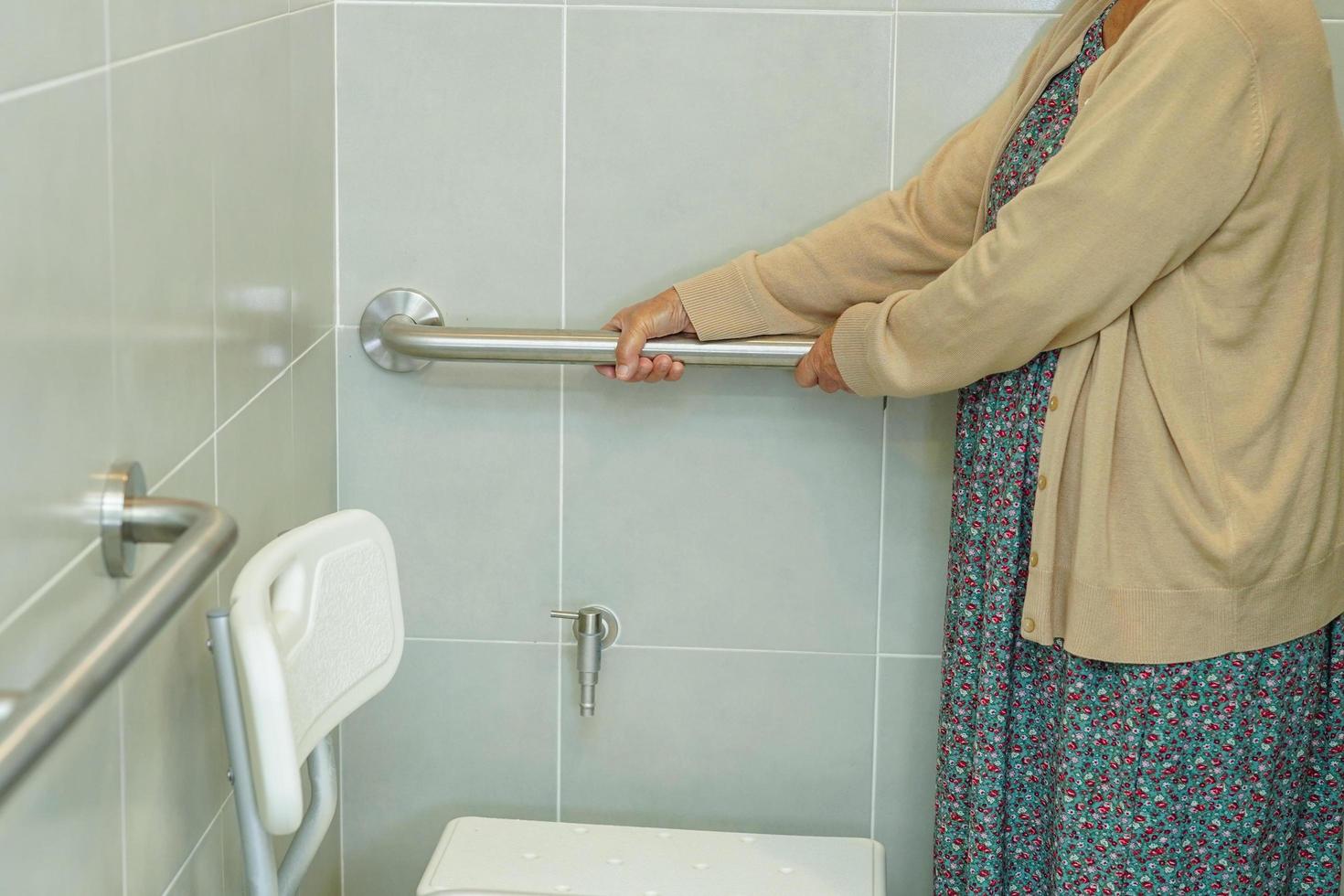 Asian elderly old woman patient use toilet support rail in bathroom, handrail safety grab bar, security in nursing hospital. photo