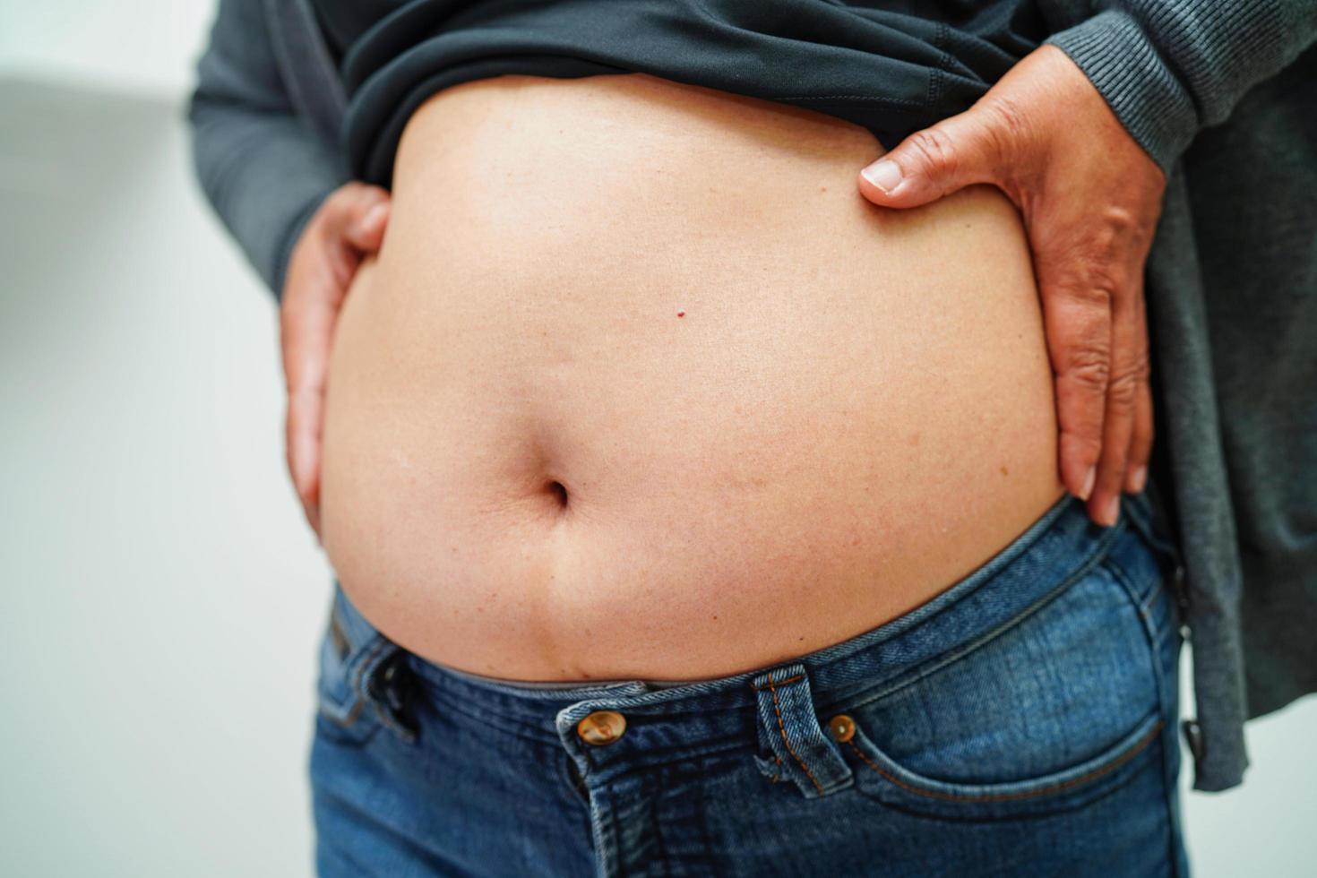 la mujer asiática muestra un vientre gordo de gran tamaño con sobrepeso y obesidad en la oficina. foto