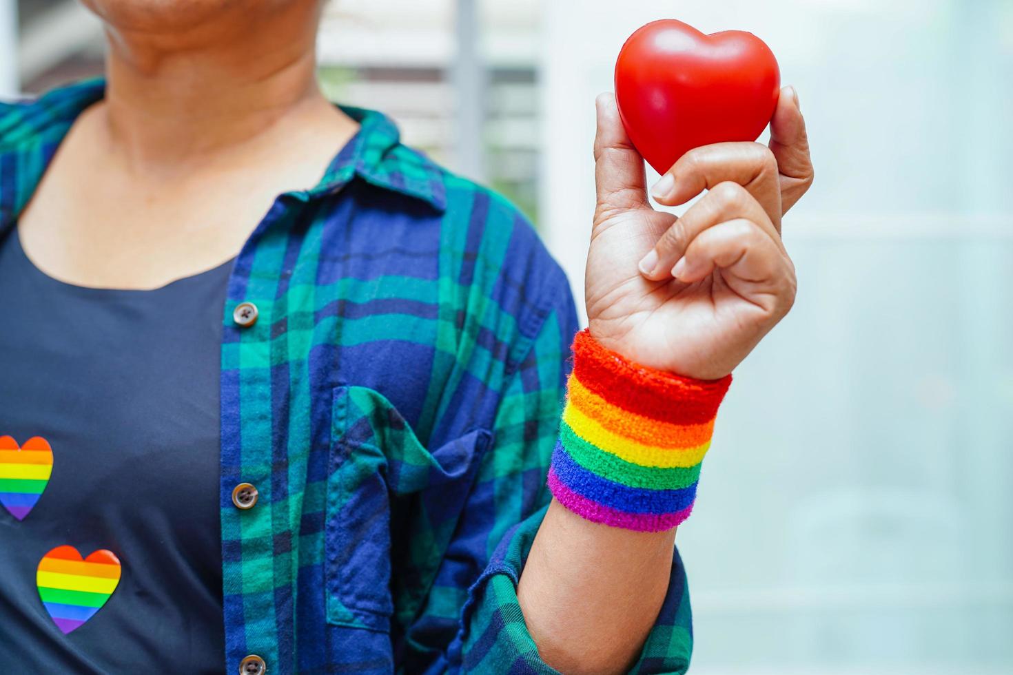 Asian woman holding red hert with rainbow flag, LGBT symbol rights and gender equality, LGBT Pride Month in June, LGBTQ, LGBTI, LGBTQA, LGBTQIA photo