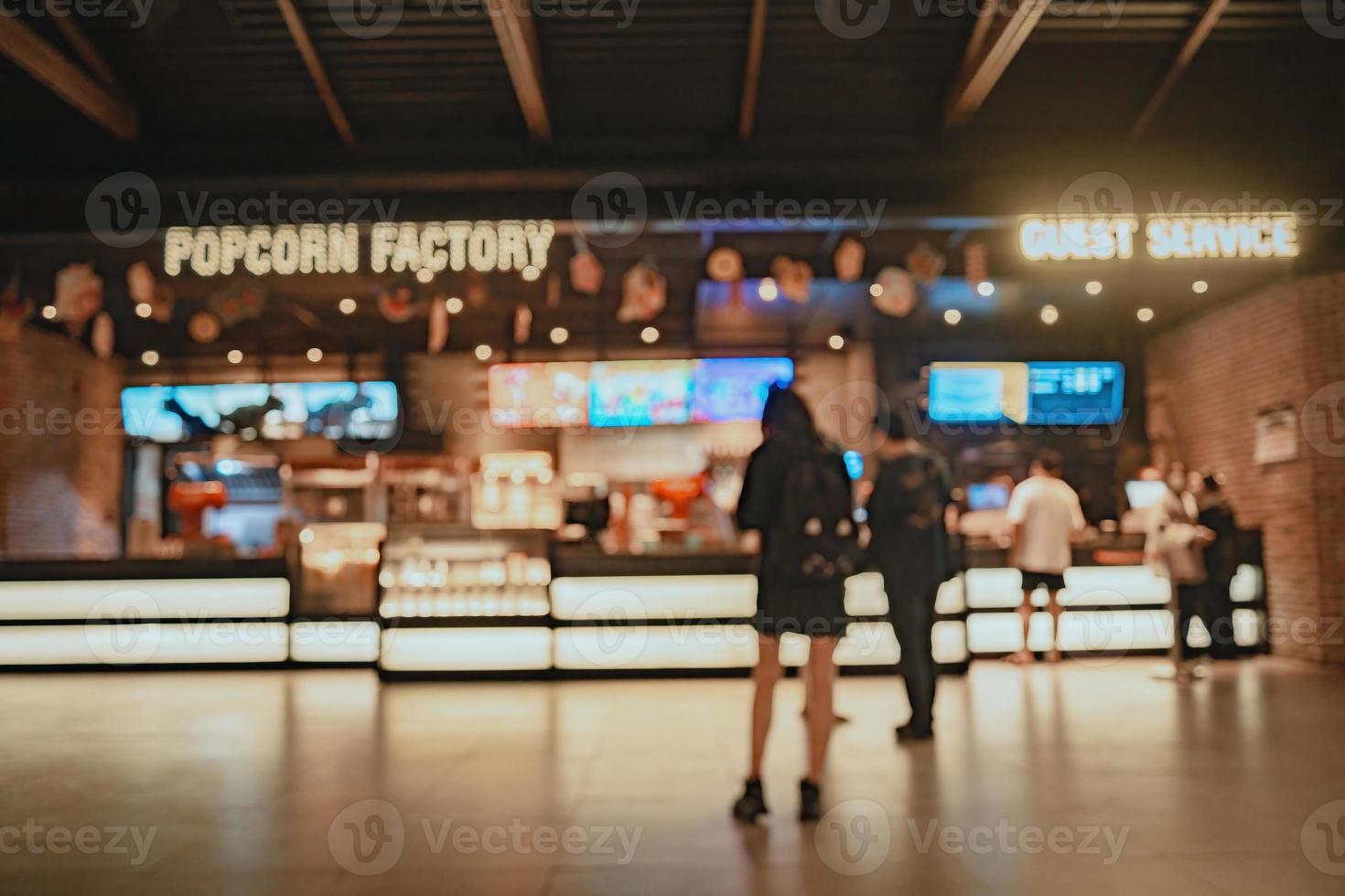 Movie theater entrance interior blur image use for background of business and cinema concept. Abstract blur people queuing to buy ticket at the counter and buy popcorn. photo