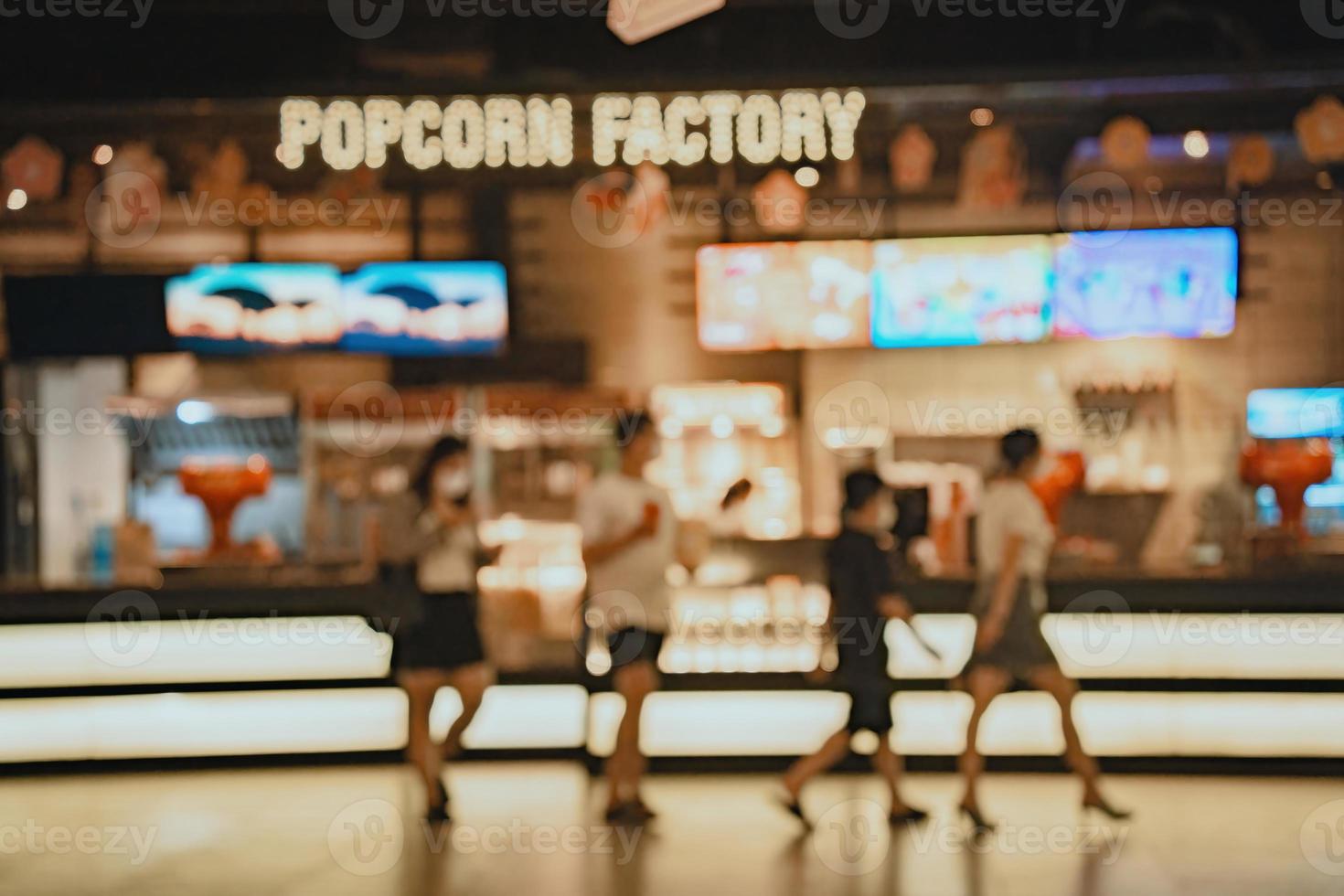 Movie theater entrance interior blur image use for background of business and cinema concept. Abstract blur people queuing to buy ticket at the counter and buy popcorn. photo