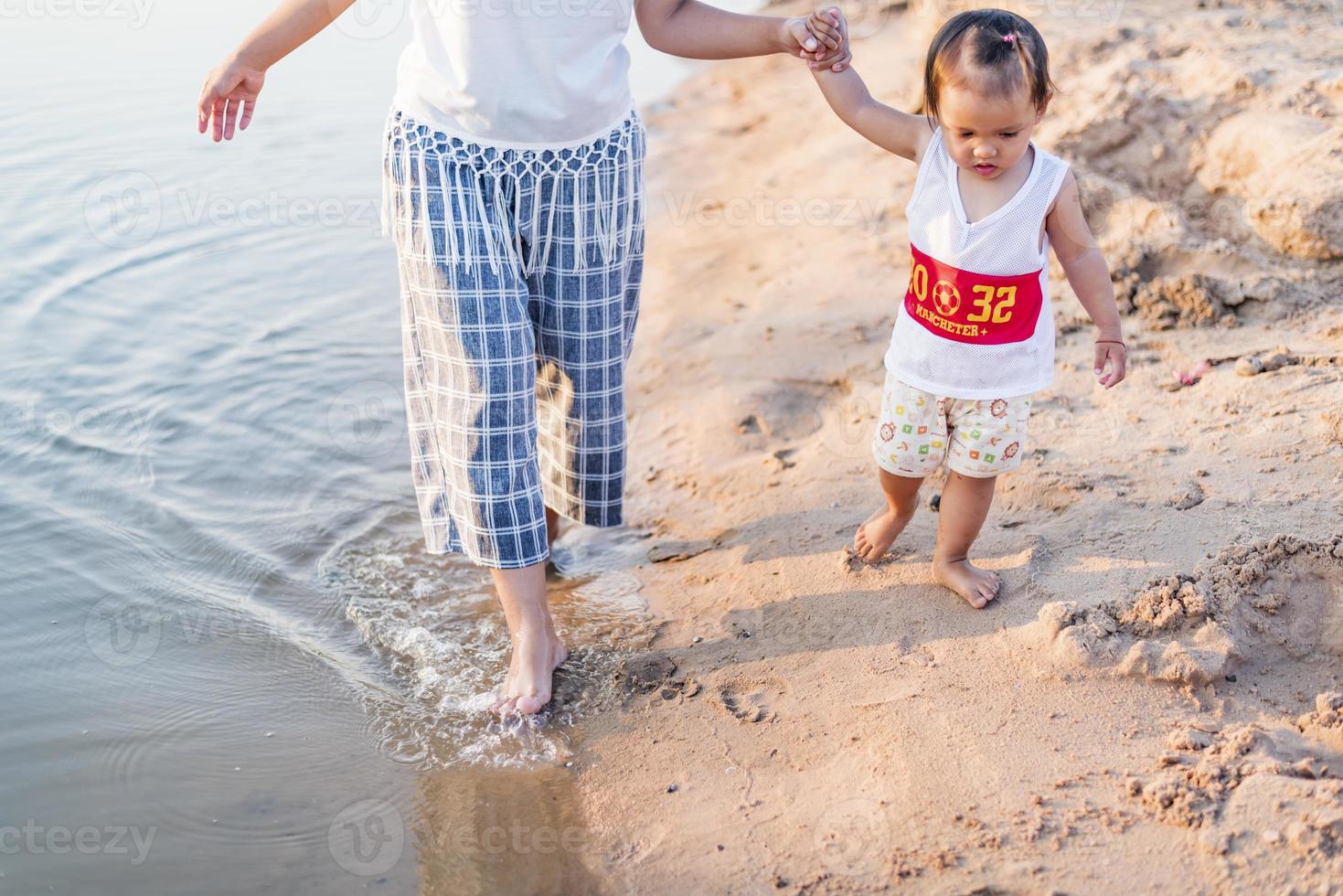 A young mother plays with her 2-5 year old daughter on the beach in summer. Outdoor resort on the lake Have a good rest on weekends, family days. photo