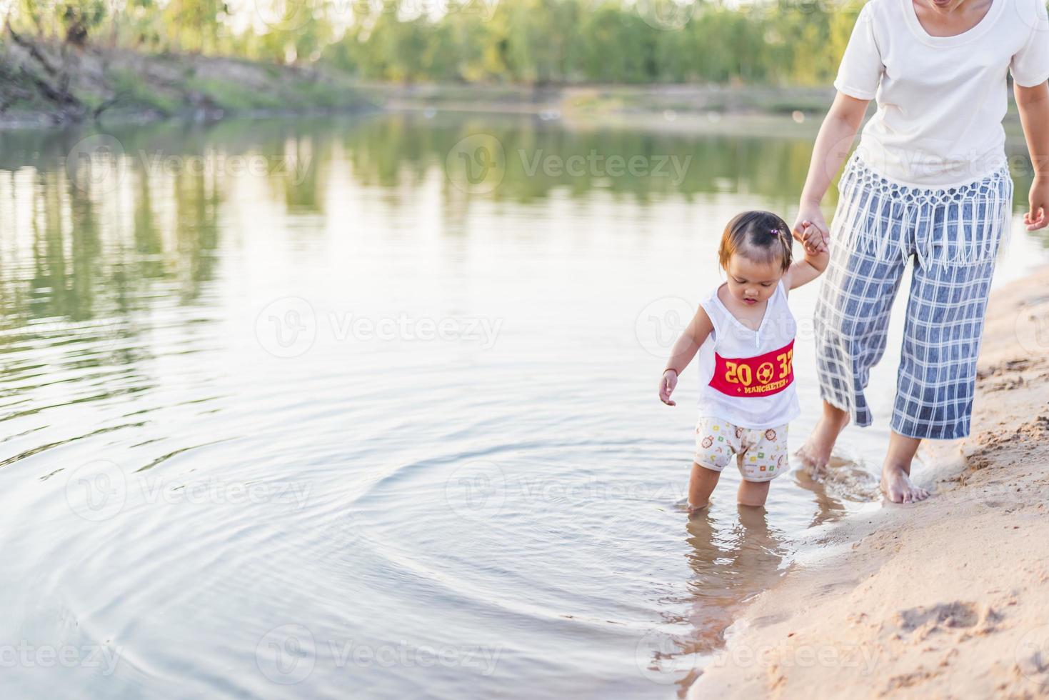 A young mother plays with her 2-5 year old daughter on the beach in summer. Outdoor resort on the lake Have a good rest on weekends, family days. photo
