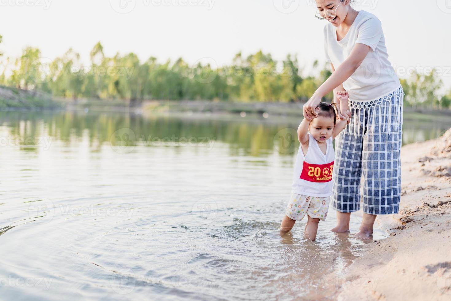 A young mother plays with her 2-5 year old daughter on the beach in summer. Outdoor resort on the lake Have a good rest on weekends, family days. photo