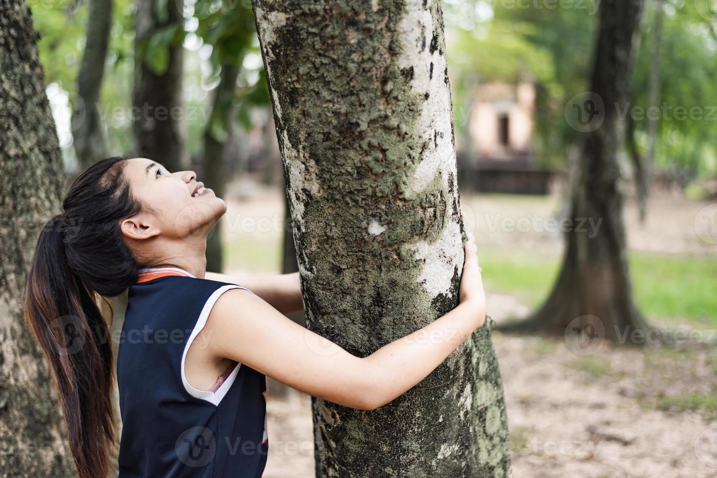 mujer joven abrazando un gran árbol, ama el concepto de naturaleza. foto