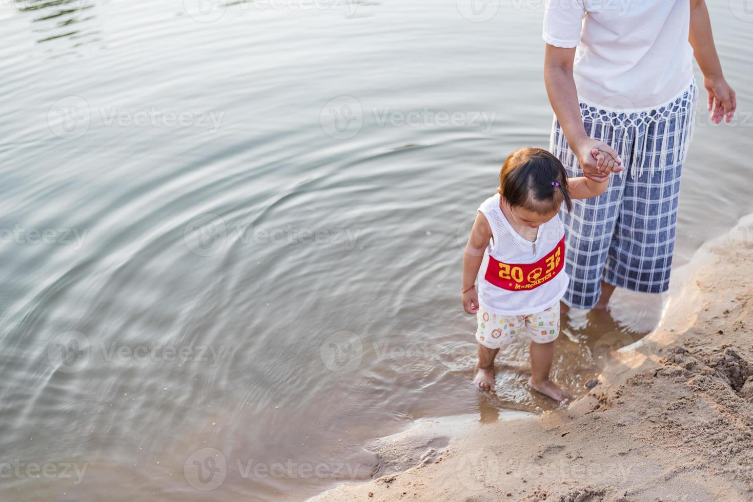 A young mother plays with her 2-5 year old daughter on the beach in summer. Outdoor resort on the lake Have a good rest on weekends, family days. photo