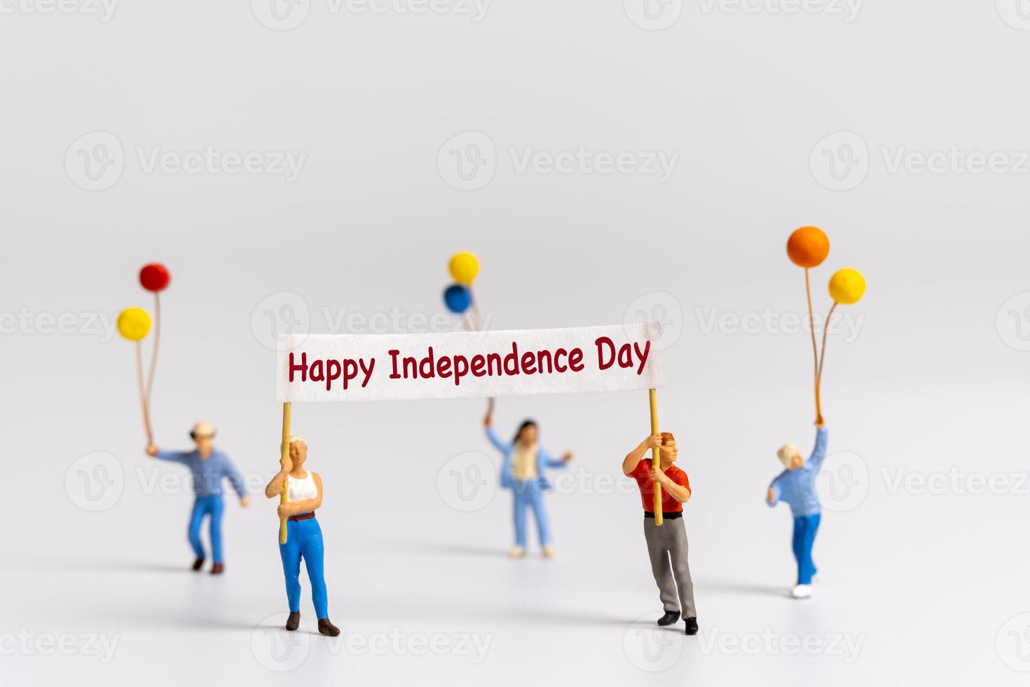 Miniature people holding flags with word Happy Independence day photo