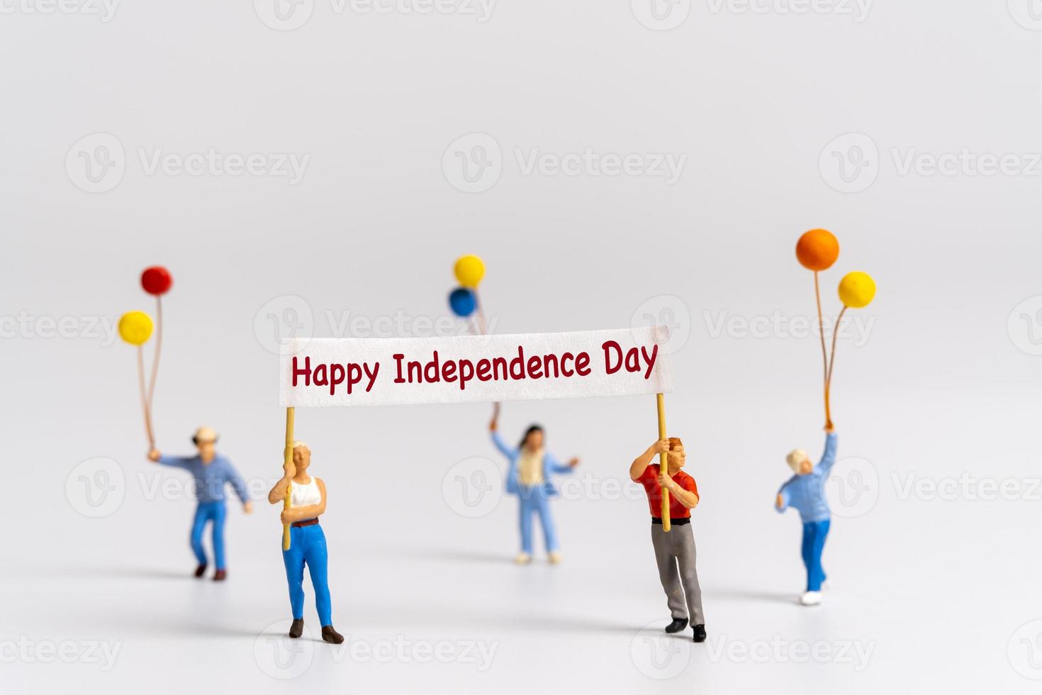 Miniature people holding flags with word Happy Independence day photo