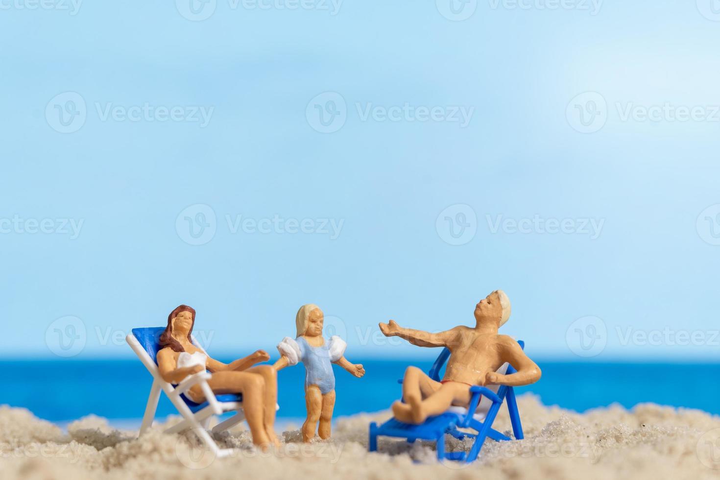 Miniature people Happy family relaxing on The beach photo