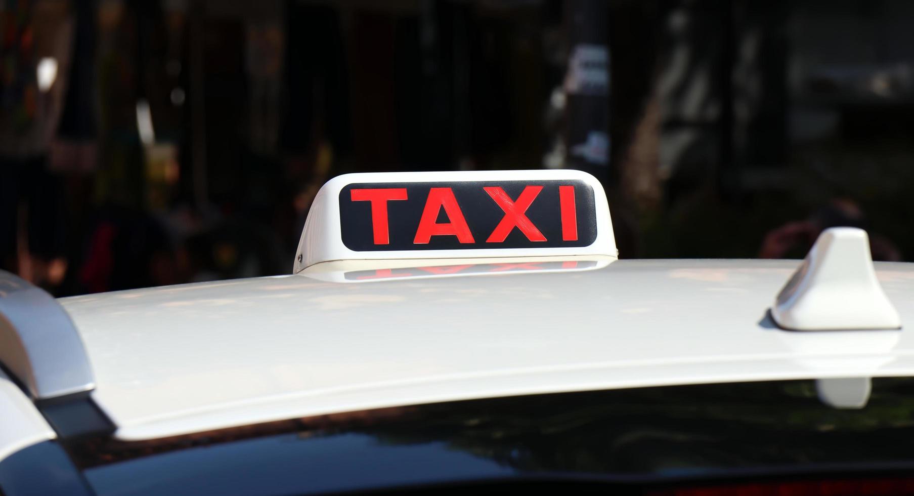 A red Taxi sign on a taxi in the city. photo