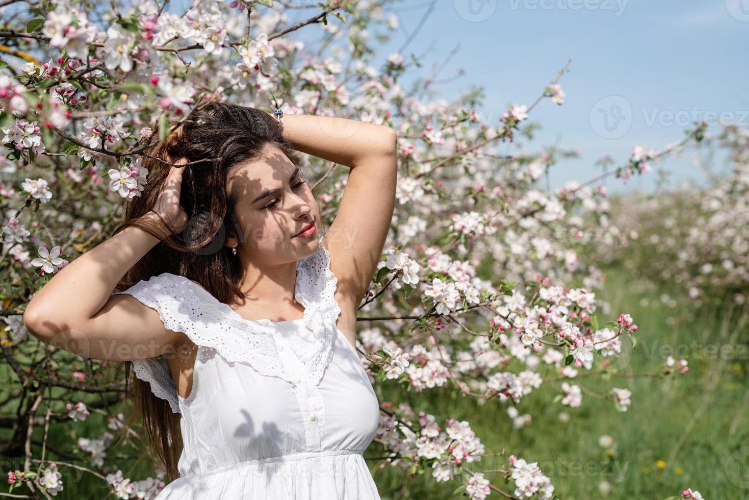 Young caucasian woman enjoying the flowering of an apple trees photo