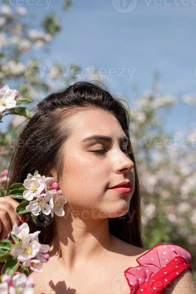 joven mujer caucásica disfrutando del florecimiento de un manzano foto