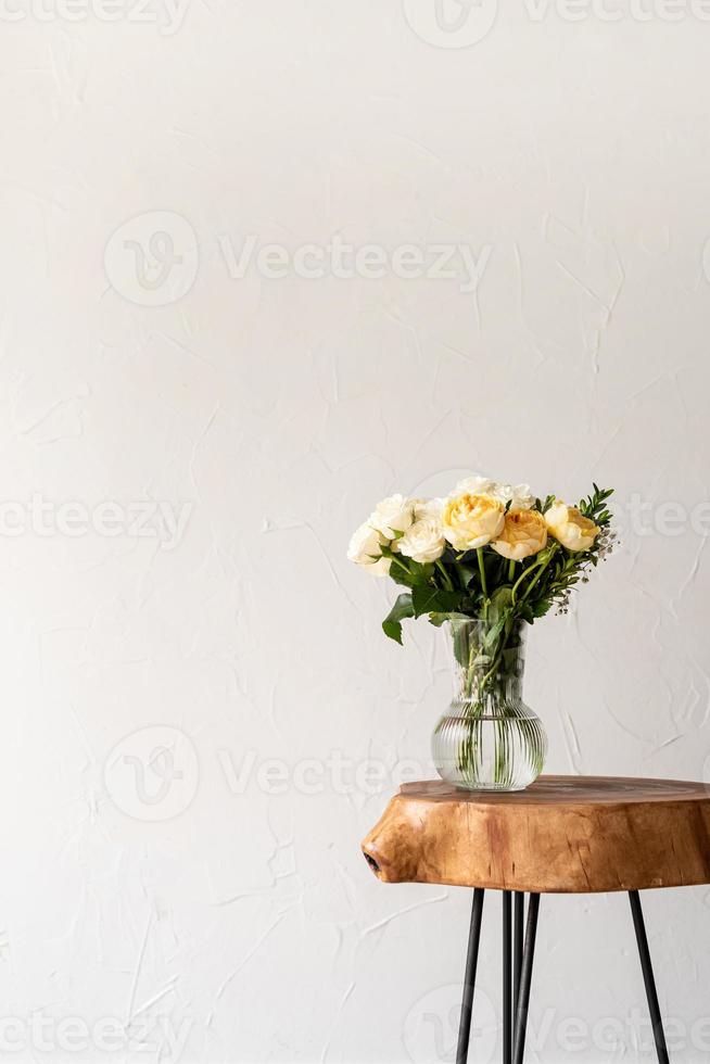 minimal home interior with stylish wooden coffee table and bouquet of fresh roses photo