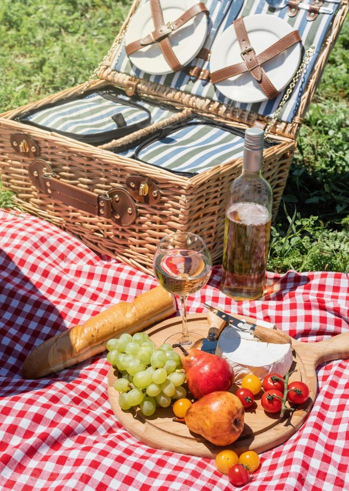 Closeup of picnic basket with drinks and food on the grass photo