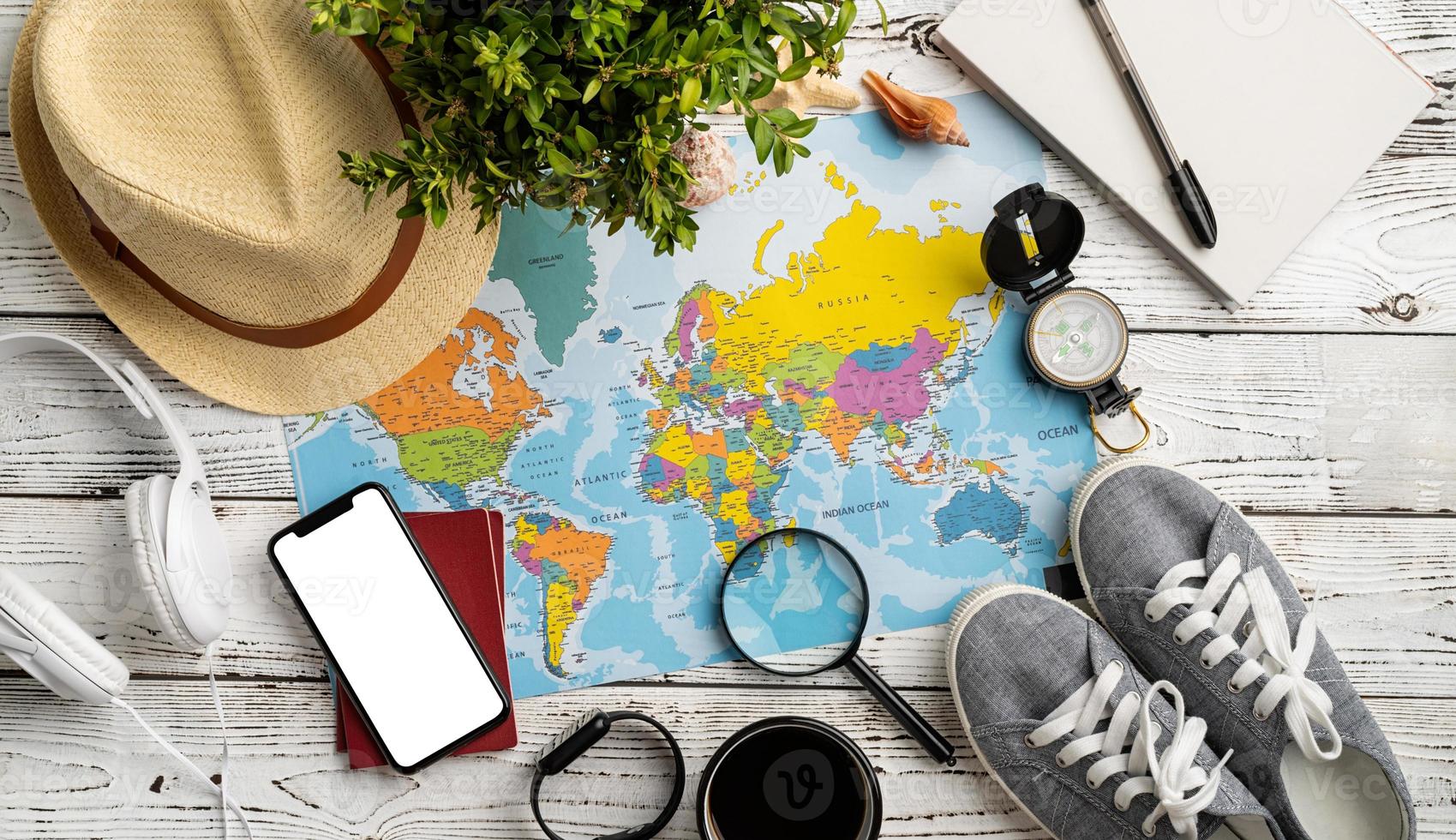 Top view travel accessories with shoes, map, smartphone with mockup screen, hat. Tourist essentials. photo