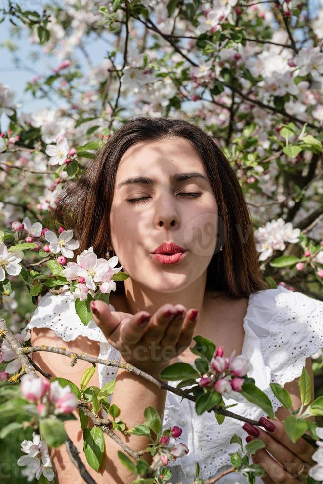 joven mujer caucásica disfrutando del florecimiento de un manzano foto