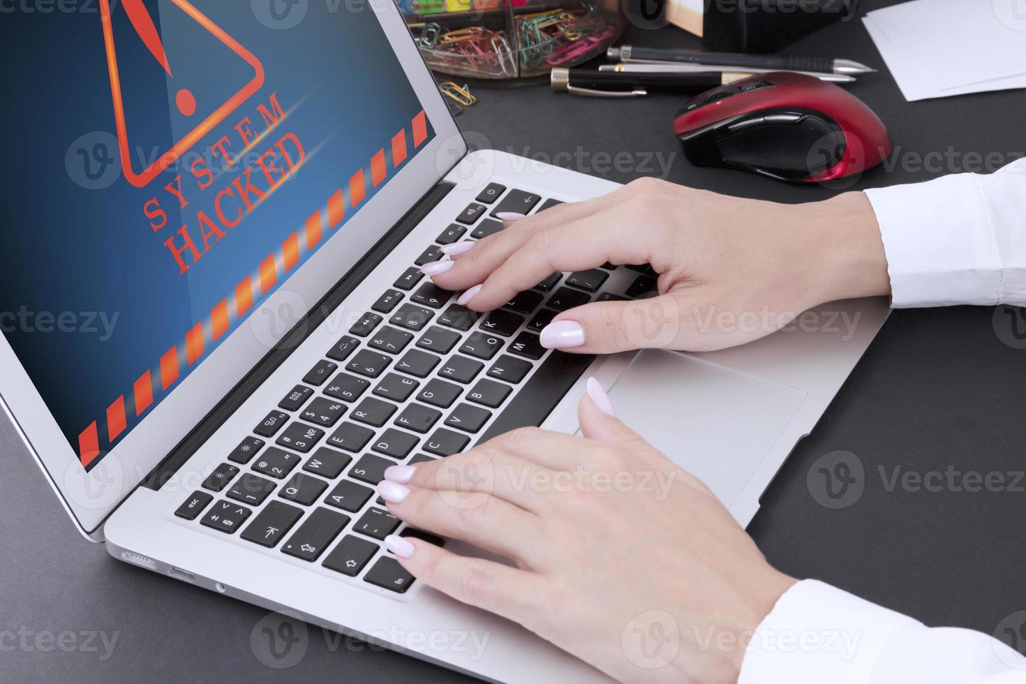 manos femeninas con manicura en el teclado de la computadora portátil y advertencia en la pantalla de la computadora. sistema hackeado. foto