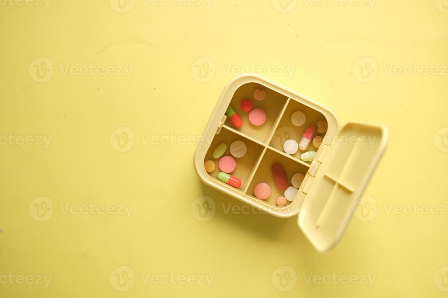 primer plano de píldoras médicas en una caja de pastillas sobre fondo amarillo foto
