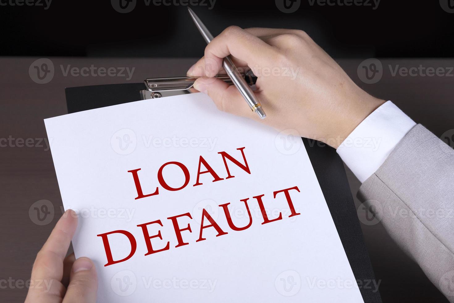 Loan default, businessman is holding a white sheet of paper and a pen with text. Business crisis concept photo