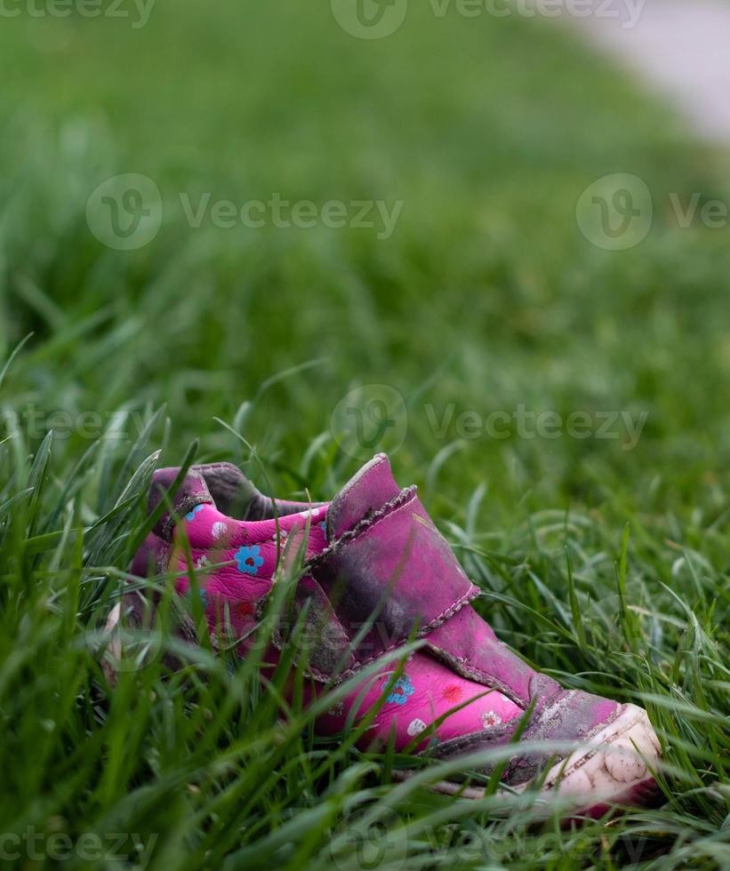 Pink child shoe in the grass photo