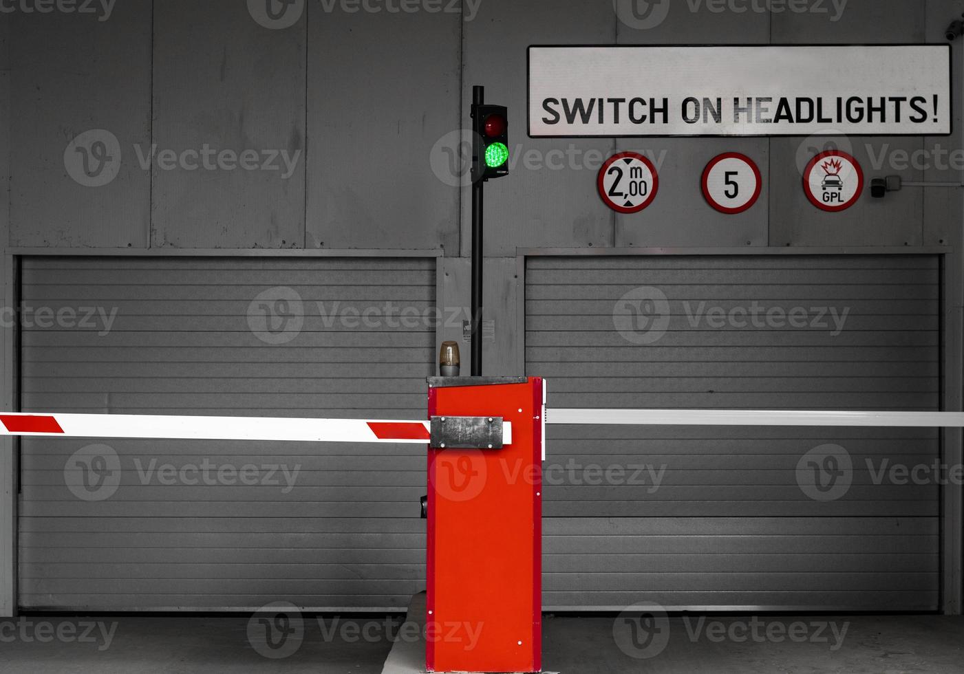 Subterranean parking garage entry gate with switch on headlights sign photo
