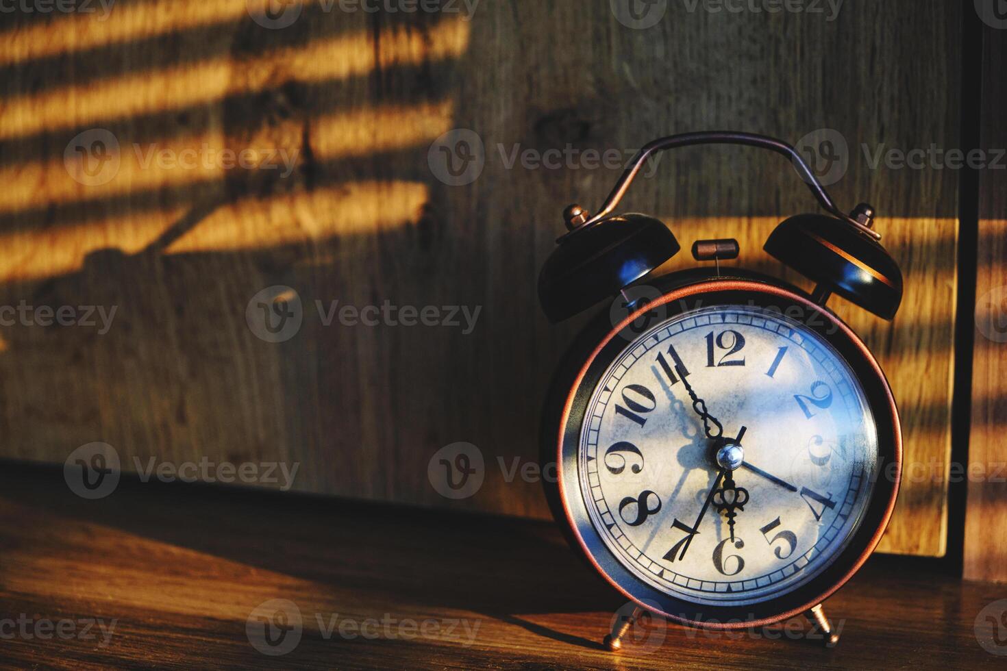 Retro alarm clock early morning on table rays sunlight through blinds