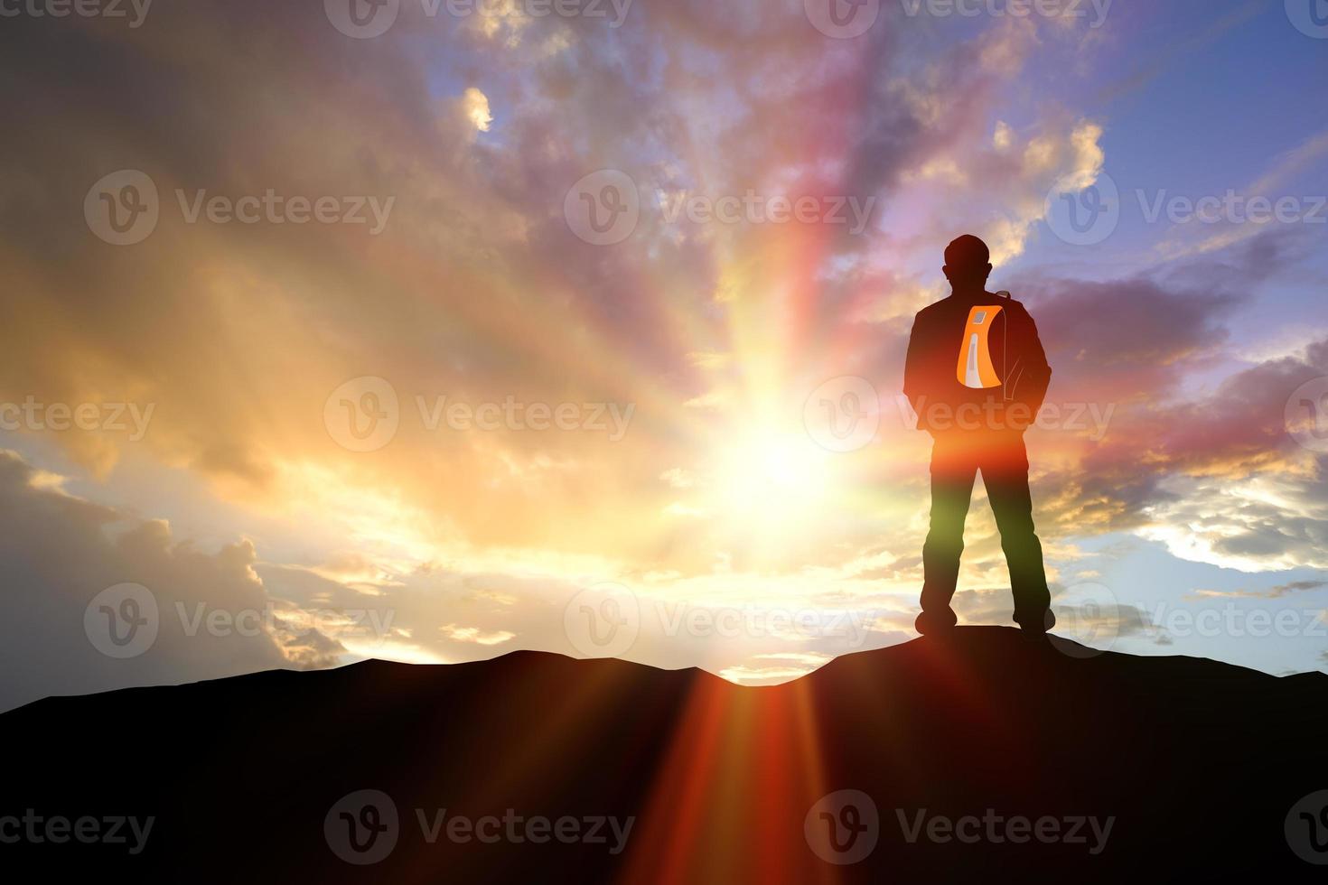 Man hiking silhouette accomplish in mountains. Silhouette man standing on the mountain looking distance. photo