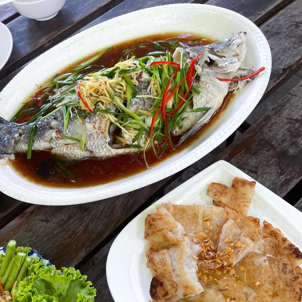 el pargo se cocina al vapor con salsa de soya y se sirve con fideos de tapioca fritos. vista superior al estilo de la comida tailandesa. menú de pescado. foto