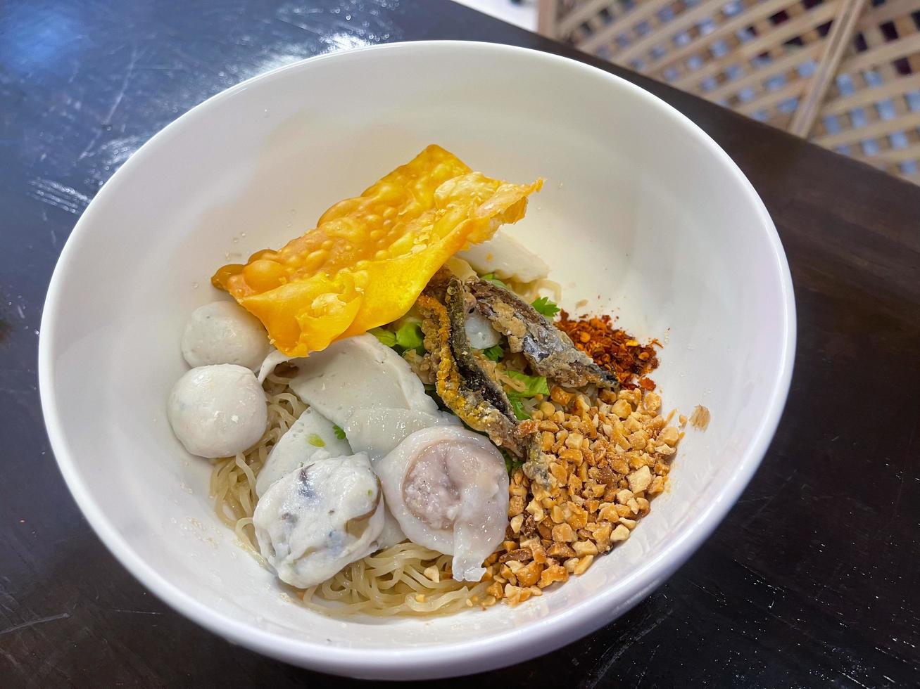 Thailand traditional dry noodles served with fish ball, fried tofu and other. A popular delicious street food of Thai peoples. Asian food. photo