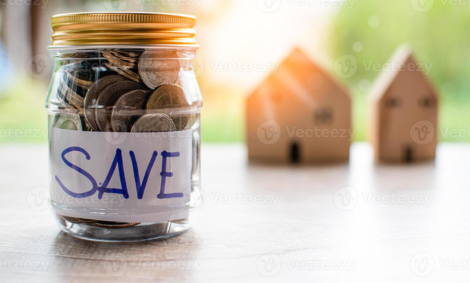 Coins and text SAVE in a glass jar placed on a wooden table. Concept of saving money for investment and buy a home. Copy space, Blurred background photo