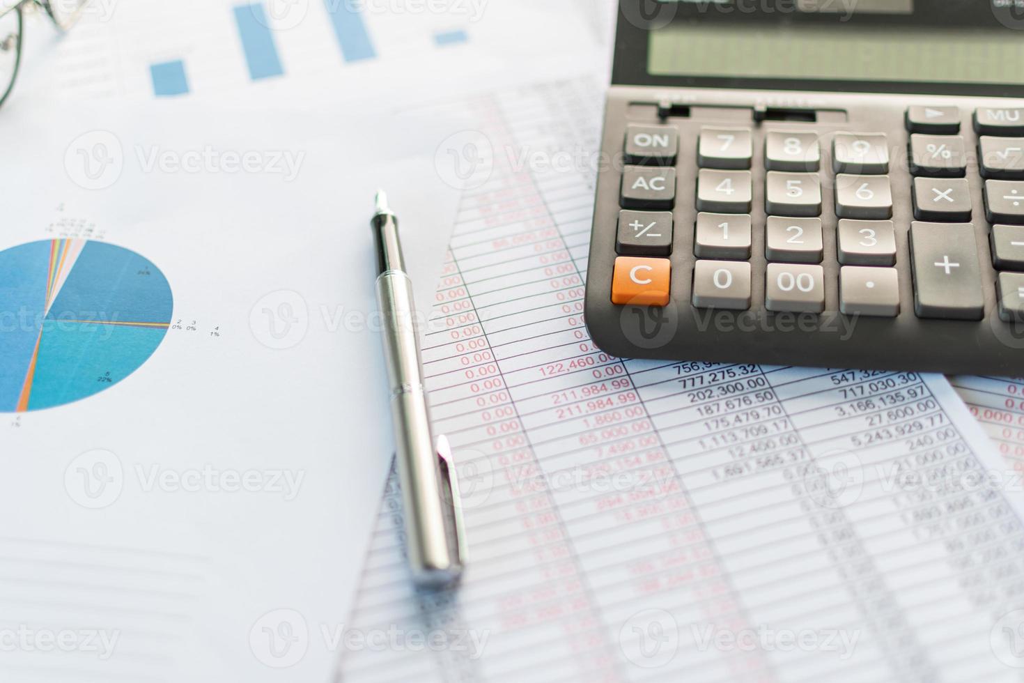 financial accounting, work from home, closeup calculator on desktop, check account number on paper and calculator, lots of numbers, graph, pen, glasses on paper, blurry background photo