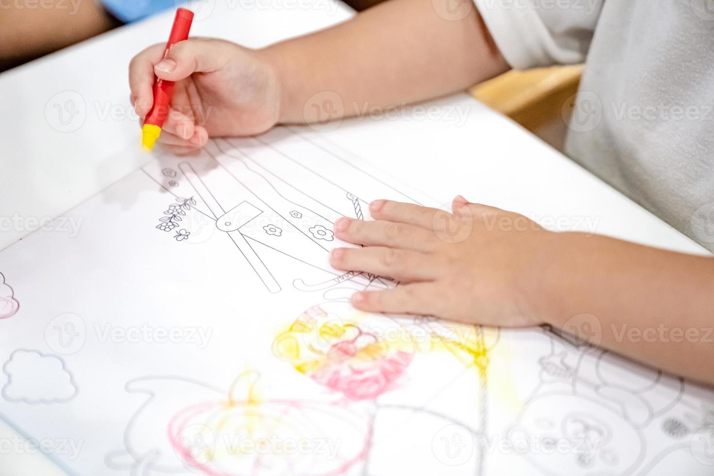 little girl plays and learns to coloring Crayon on the paper in the ice-cream restaurant., Bangkok, Thailand. photo