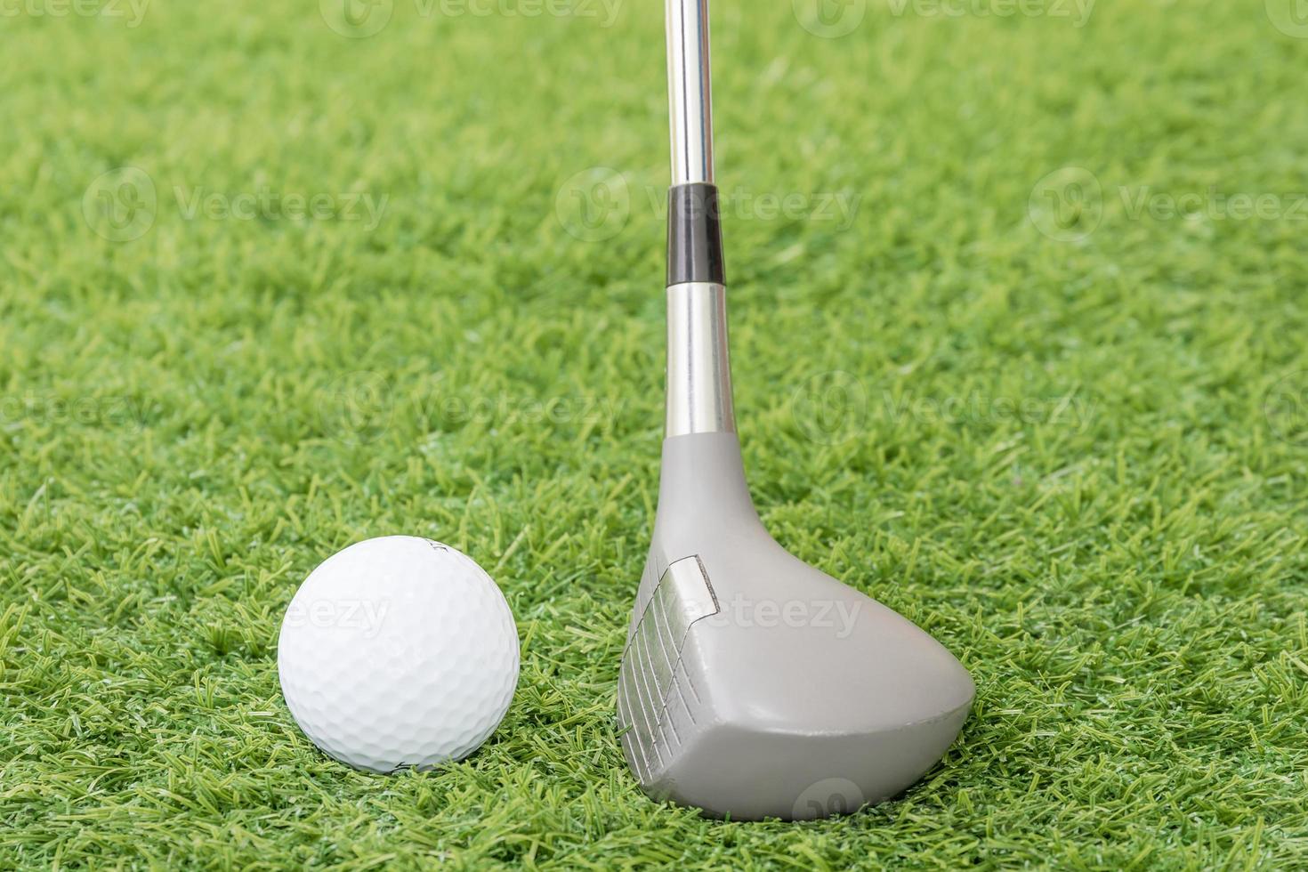 Golf ball and golf club on green grass photo