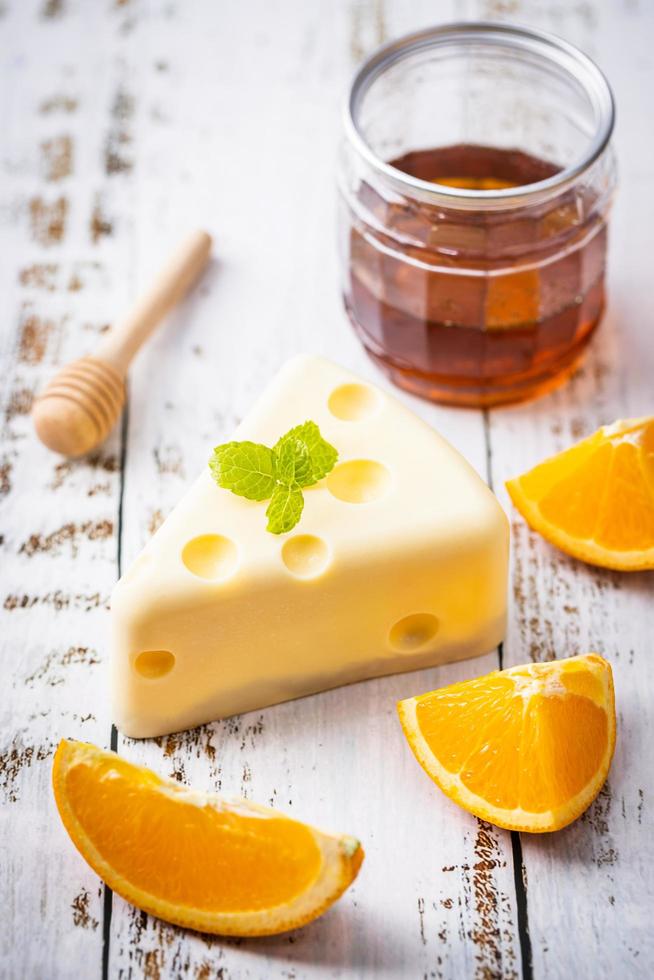 Homemade of Fresh white chocolate cake in cheese shape putt on white wooden table and mint, orange, honey scoop, and honey. Sweet Food and Dessert concept. Sweets decorated for holiday. Close-up. photo