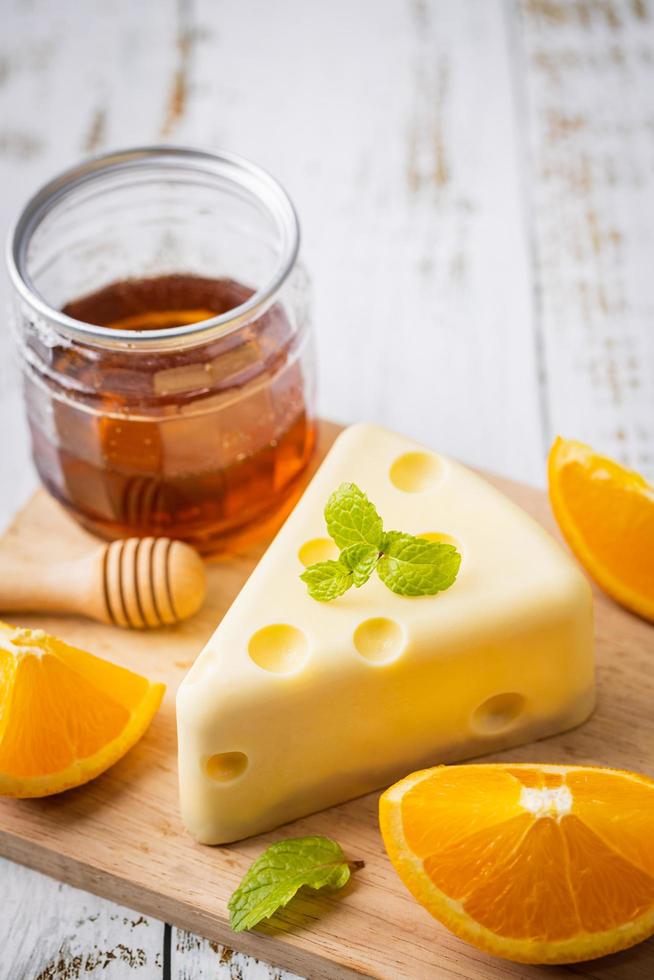 Homemade of Fresh white chocolate cake in cheese shape putt on white wooden table and mint, orange, honey scoop, and honey. Sweet Food and Dessert concept. Sweets decorated for holiday. Close-up. photo