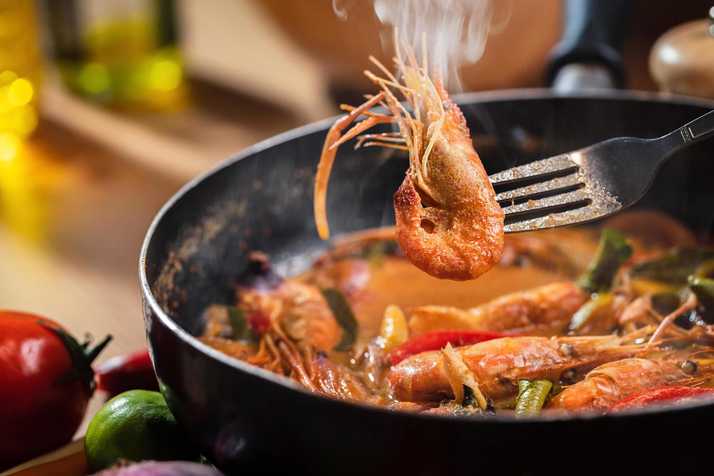 Tom Yum Goong or Tom Yum Kung, Thai hot and sour shrimp soup in pan. Thai food in Thai cuisine restaurant. Use a fork to lift the shrimp out of the pan. Shrimp and Spices in coconut milk. Closeup photo