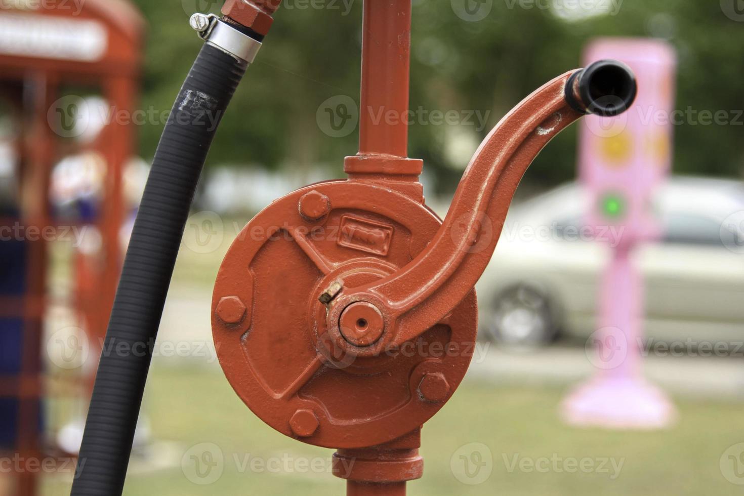 old-fashioned, vintage red hand crank gas station stands in the park to decorate the garden and give it to the younger generation. photo