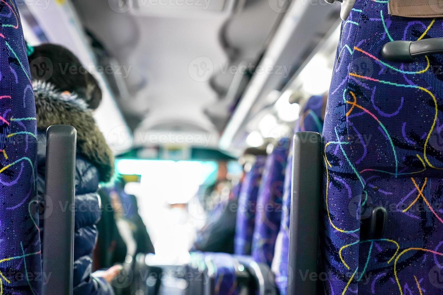 People on the bus were sitting listen to tour guide who standing at front of row photo