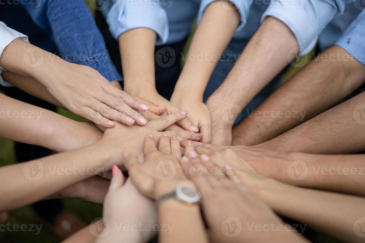 Close up to Asian people hold hand together in the middle of their group, friend with stack of hand showing the love and community of good friends. photo