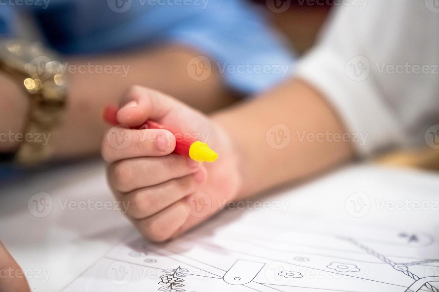 little girl plays and learns to coloring Crayon on the paper in the ice-cream restaurant., Bangkok, Thailand. photo