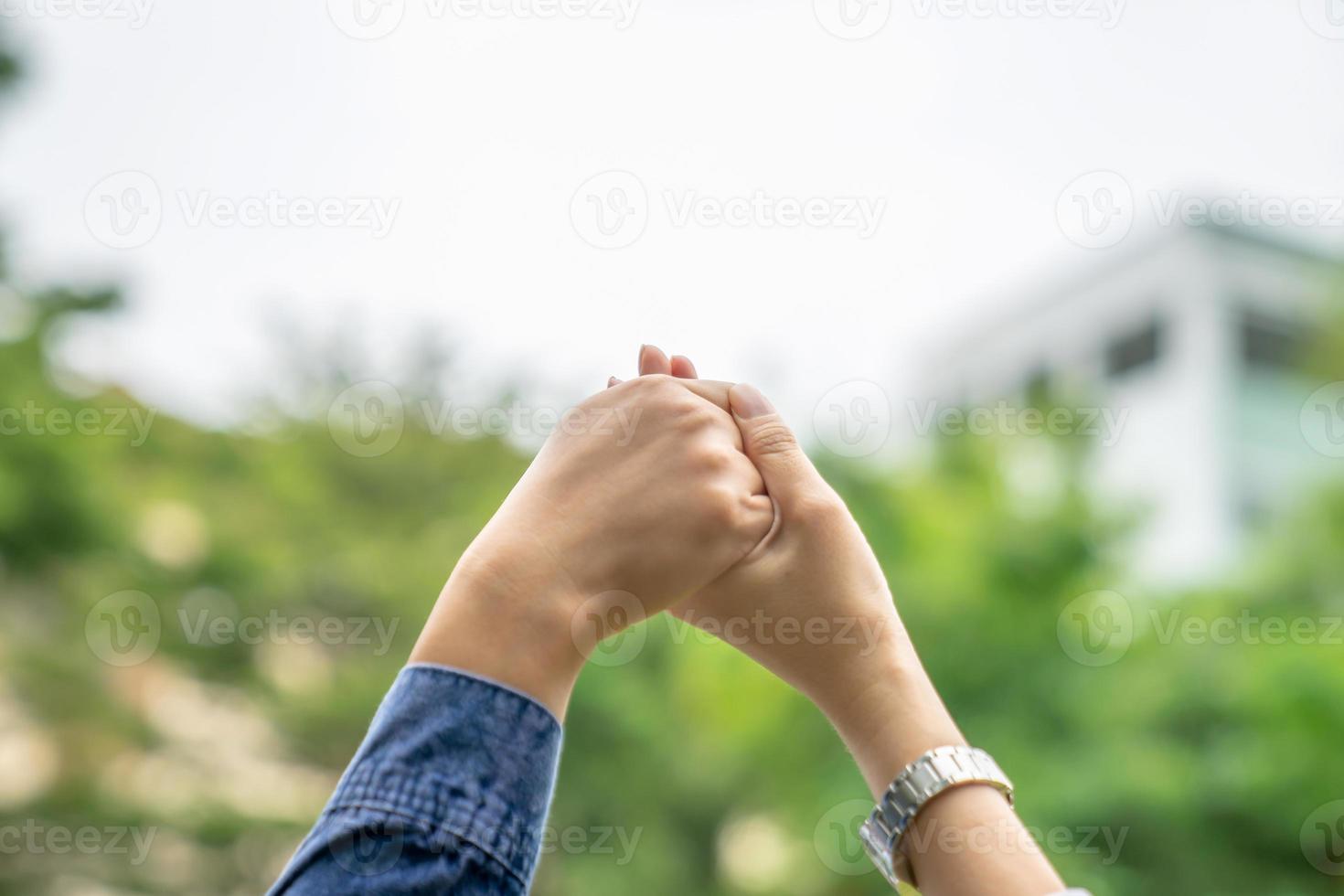 Close up to two Asian females holds hands and raise up to the sky. For showing the team building work and play together. photo