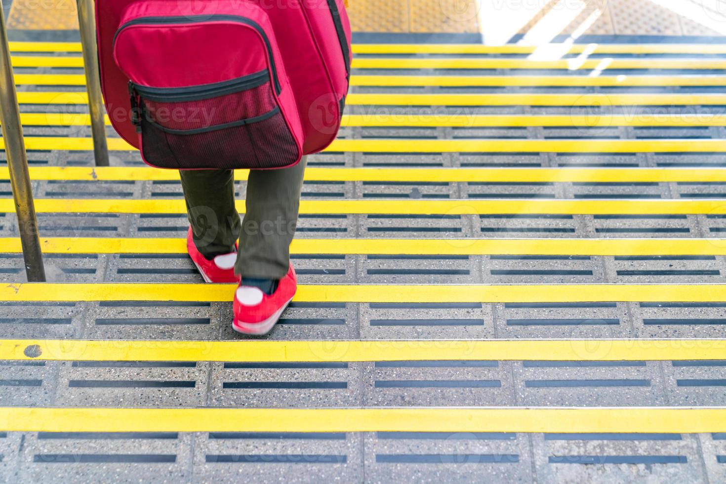 Japanese guy walking down the stair at the train station with the guitar backpack on his back. photo