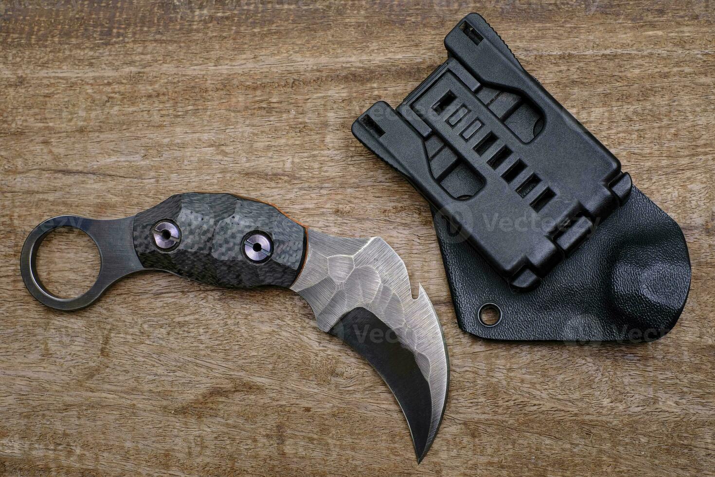 cuchillo karambit luchador táctico sobre fondo de madera foto