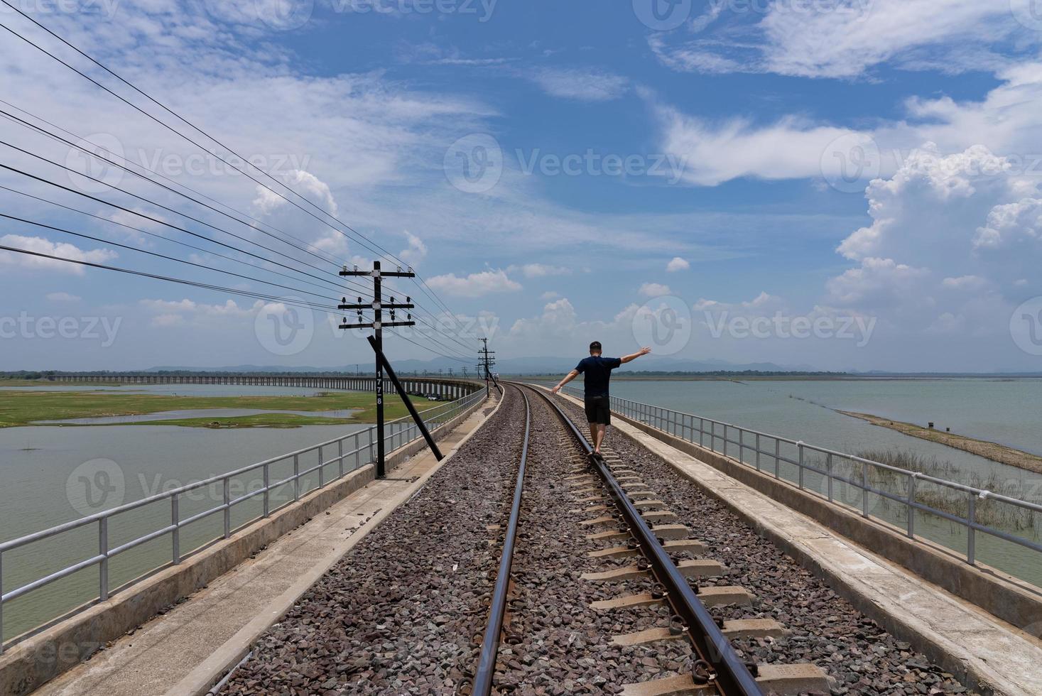 Adult man Walking on RailRoad While Travel on Summer Vacation photo