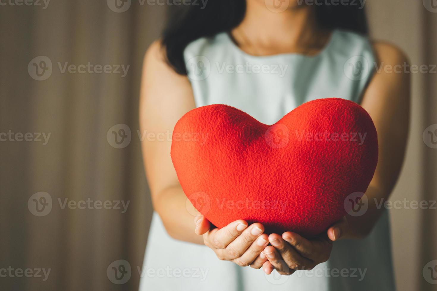 primer plano de una mujer sosteniendo un modelo de almohada de corazón para el día de san valentín, el día de la madre y el mes de concientización sobre el cáncer de mama para la atención médica del día internacional de la mujer foto